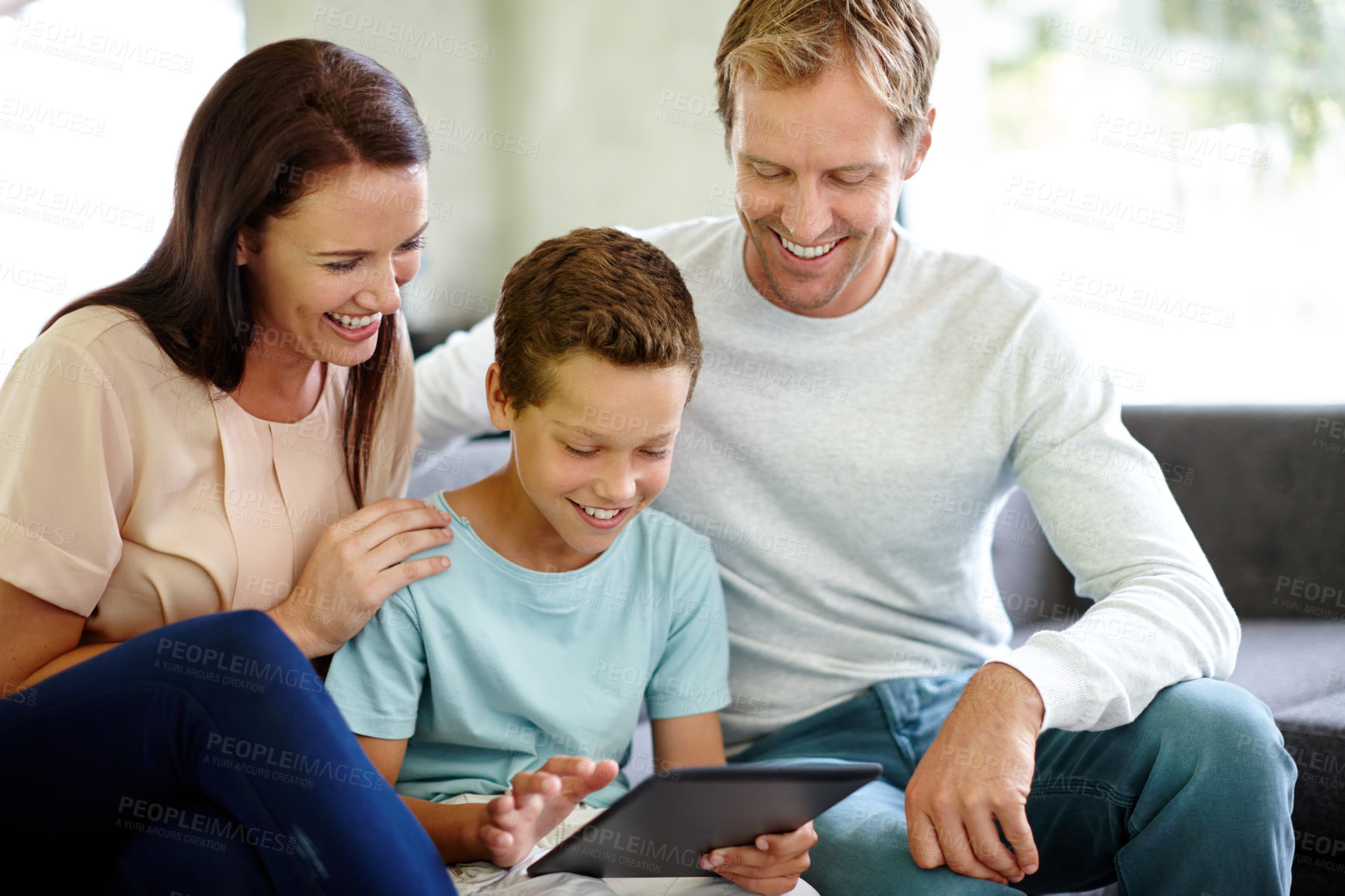 Buy stock photo Shot of a family using a digital tablet while sitting on the sofa at home