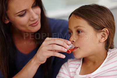 Buy stock photo Shot of a caring mother giving her sick little girl some medicine
