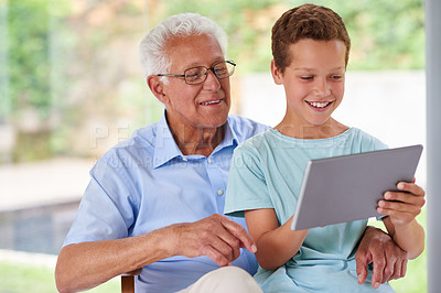 Buy stock photo A boy using a digital tablet with his grandfather
