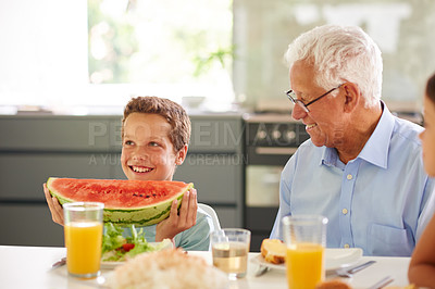 Buy stock photo Shot of a little boy holding a large slice of watermelon while his family look on