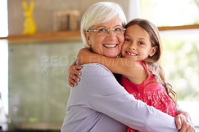 Buy stock photo Portrait of a cute little girl hugging her grandmother in a kitchen