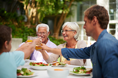 Buy stock photo Shot of a family toasting each other over a lunch outside