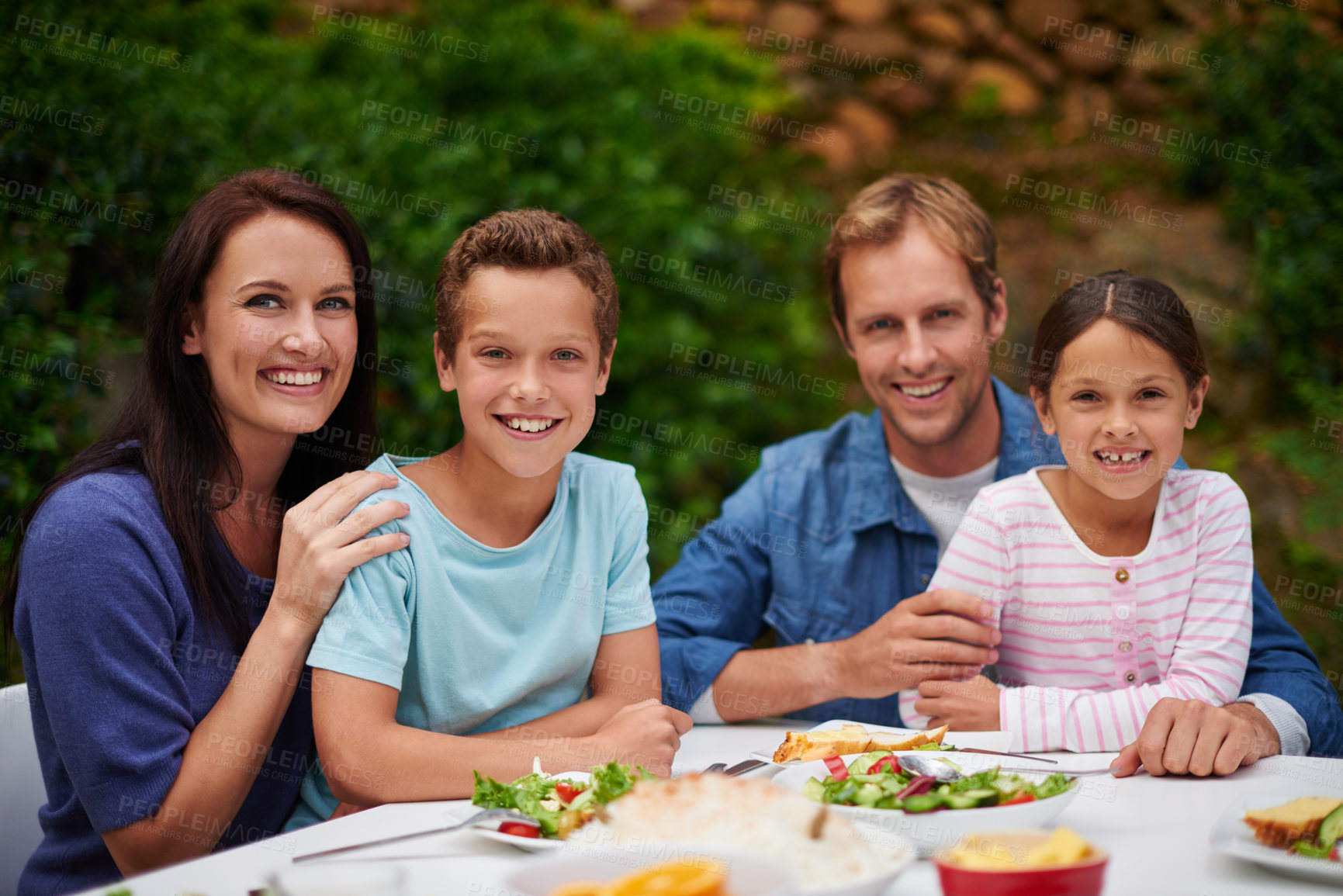 Buy stock photo Portrait of a smiling family enjoying a meal on their patio