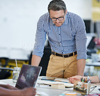 Buy stock photo Shot man looking over paperwork with colleagues in an office