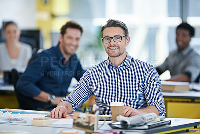 Buy stock photo Portrait of an office worker sitting at his desk with colleagues in the background