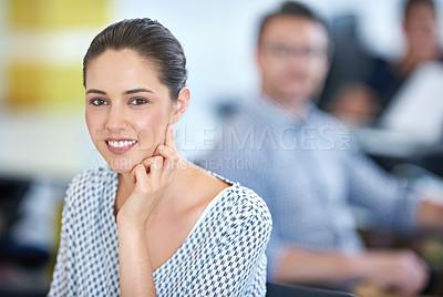 Buy stock photo Portrait of a designer sitting at her desk with colleagues in the background