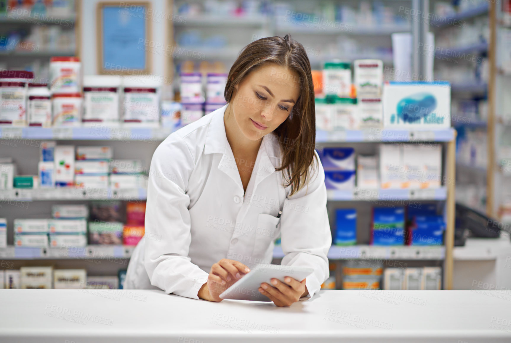 Buy stock photo Shot of an attractive young pharmacist working at the prescription counter