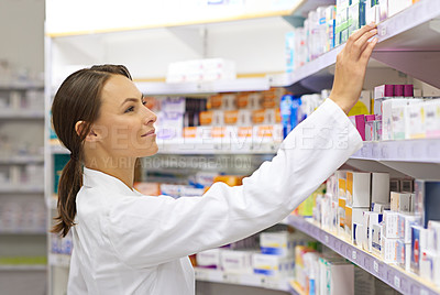 Buy stock photo Shot of an attractive young pharmacist checking stock in an aisle