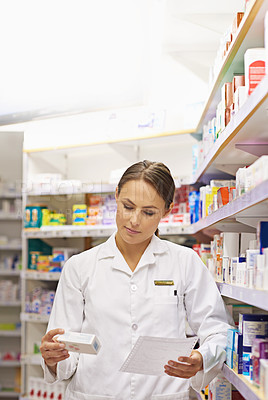 Buy stock photo Shot of an attractive young pharmacist collecting a prescription in an aisle