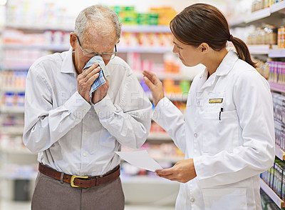 Buy stock photo Shot of a young pharmacist helping an elderly customer with a cold