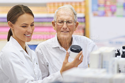 Buy stock photo Shot of a young pharmacist helping an elderly customer