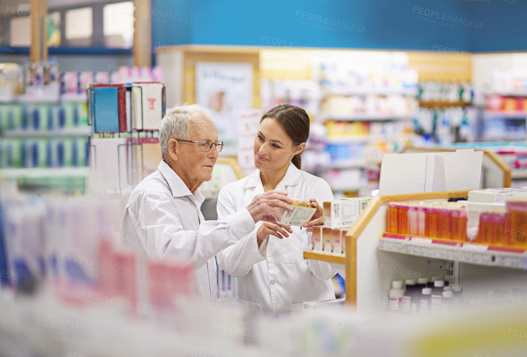 Buy stock photo Shot of a young pharmacist helping an elderly customer