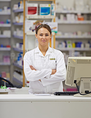 Buy stock photo Portrait of an attractive young pharmacist standing at the prescription counter