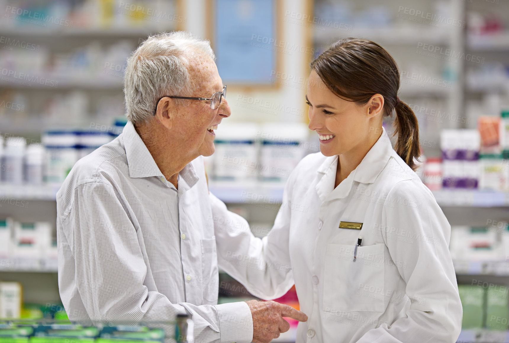 Buy stock photo Shot of a young pharmacist helping an elderly customer