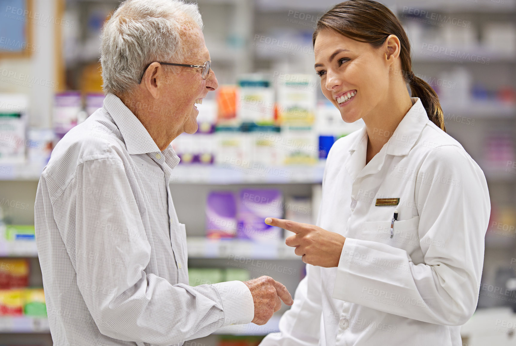 Buy stock photo Shot of a young pharmacist helping an elderly customer