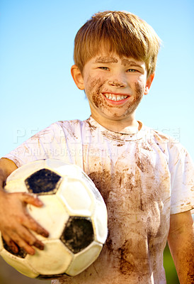 Buy stock photo Portrait, smile and kid with soccer ball outdoor for sports, exercise or game in summer. Face, boy and happy child with football with mud, messy or dirty for recreation in Switzerland on blue sky