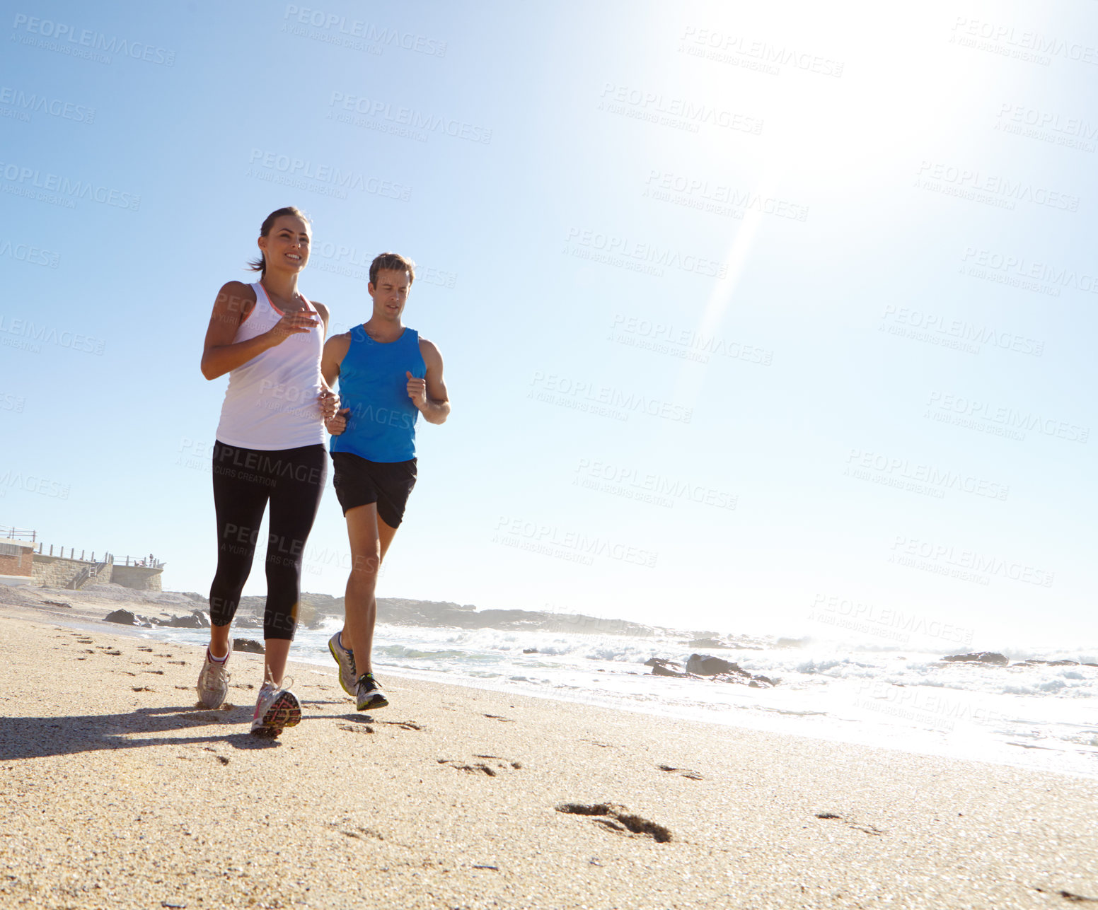 Buy stock photo Couple, running and training at beach in summer with partner, wellness and space for fitness. Man, woman and happy outdoor with low angle for exercise, workout or cardio challenge with flare by ocean
