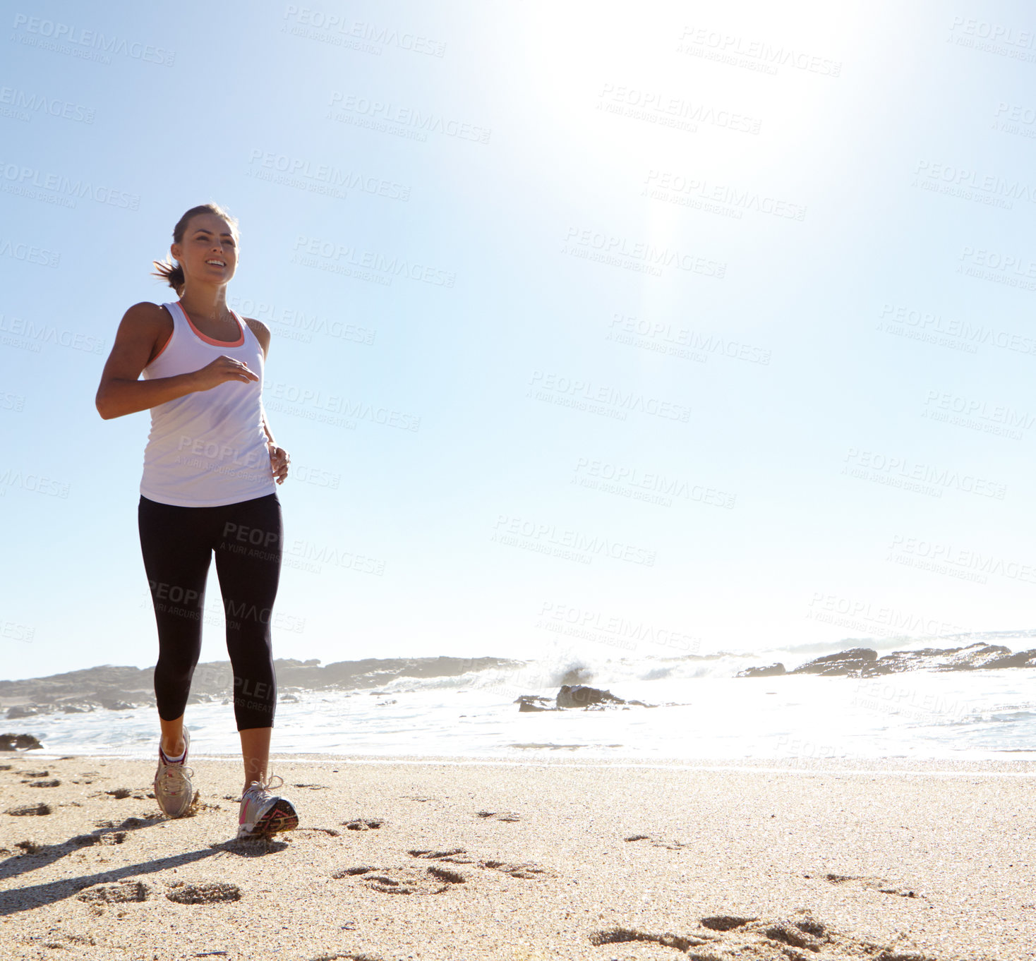 Buy stock photo Shot of a young woman jogging on the beach