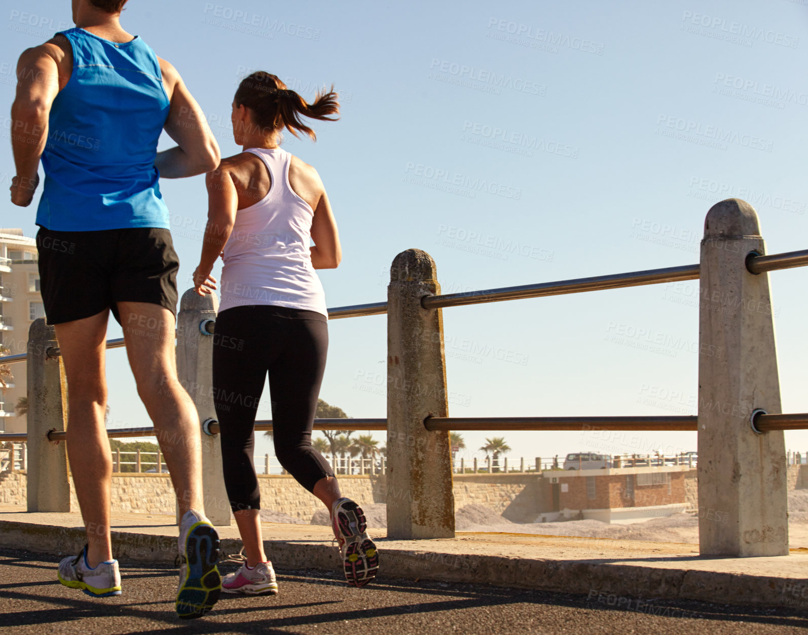 Buy stock photo Shot of a young couple jogging together on the promenade