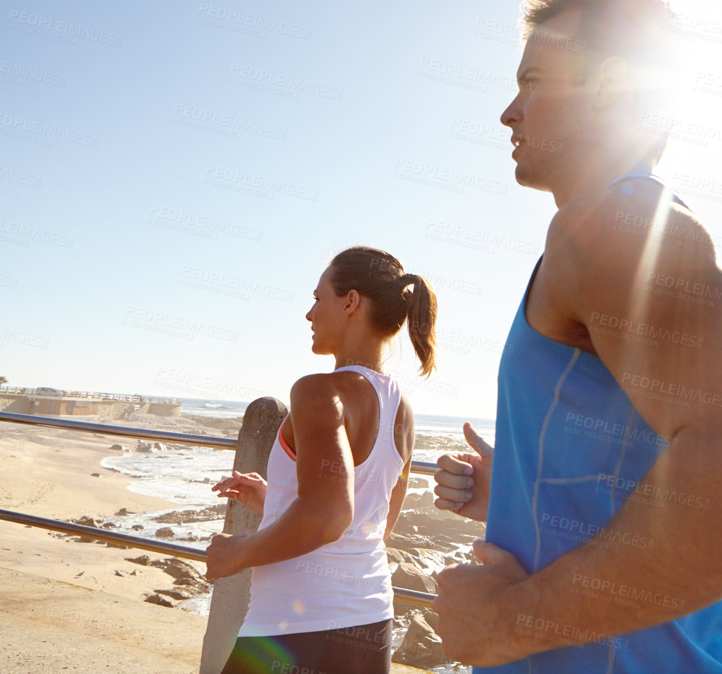 Buy stock photo Shot of a young couple jogging together on the promenade 