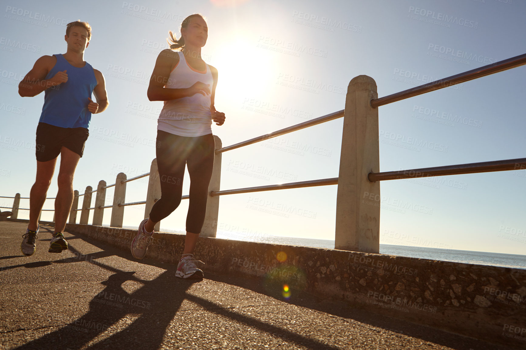 Buy stock photo Shot of a young couple jogging together the promenade 