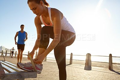 Buy stock photo Shot of an athletic woman tying her shoe laces on a bench 