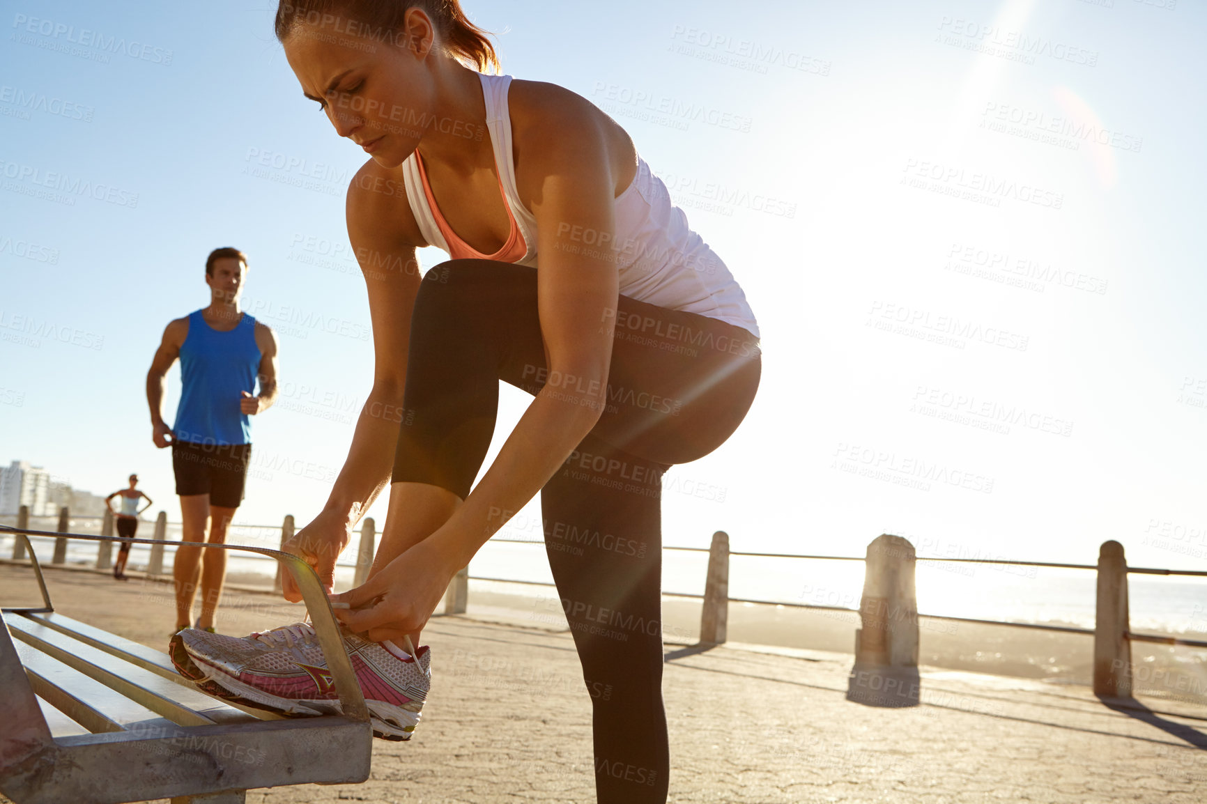 Buy stock photo Shot of an athletic woman tying her shoe laces on a bench 