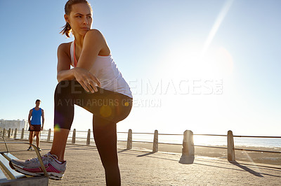 Buy stock photo Shot of a woman in sportswear taking a break after a jog with a man in the background