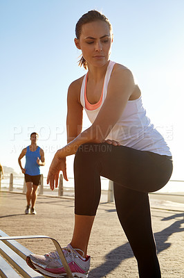 Buy stock photo Shot of a woman in sportswear taking a break after a jog with a man in the background