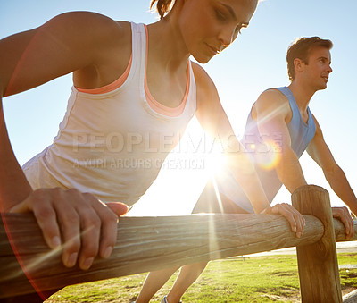 Buy stock photo A young couple doing push ups against a wooden fence