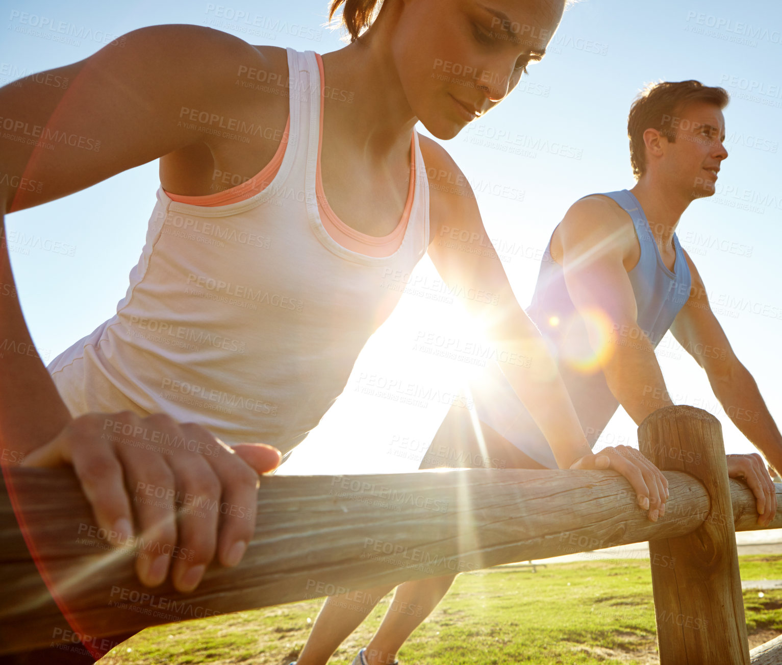 Buy stock photo A young couple doing push ups against a wooden fence