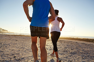 Buy stock photo Shot of a young couple jogging together on the beach