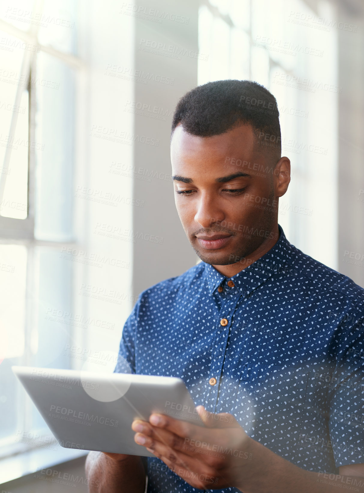 Buy stock photo Businessman, tablet and reading at window for communication, internet search or networking in office. Entrepreneur, african employee or serious with technology for startup email or planning at work