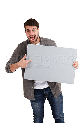 Buy stock photo Studio shot of a smiling young man holding a blank poster and pointing to it excitedly