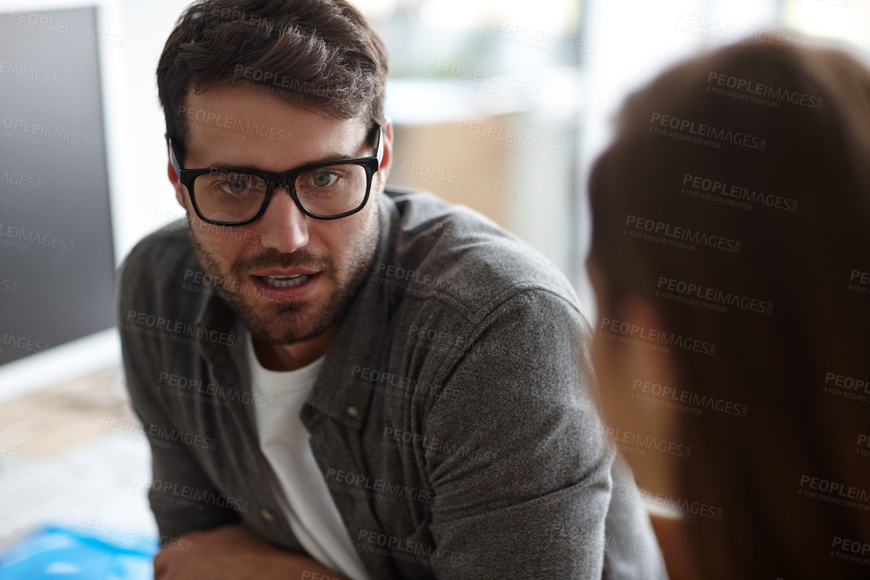 Buy stock photo Shot of a young designer conversing seriously with a colleague