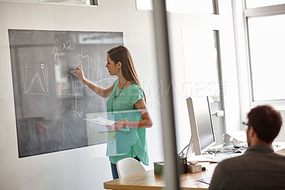 Buy stock photo Shot of a young designer describing her statistical analysis on a blackboard