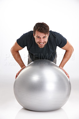 Buy stock photo Studio shot of a smiling young man doing pushups on an exercise ball