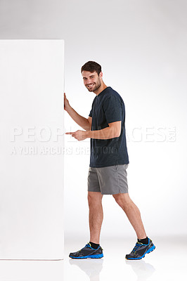 Buy stock photo Happy man, portrait and pointing with billboard for fitness, advertising or sports fashion on a white studio background. Male person, model or smile with mockup space for sign up or gym membership