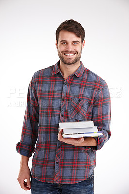 Buy stock photo Studio portrait of a smiling young man holding a pile of books in one arm