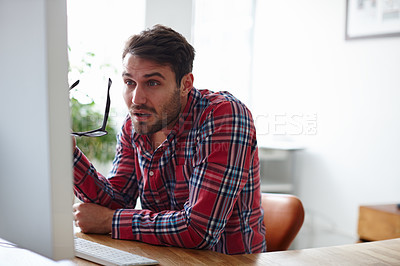 Buy stock photo Shot of a young designer squinting at the screen of his computer