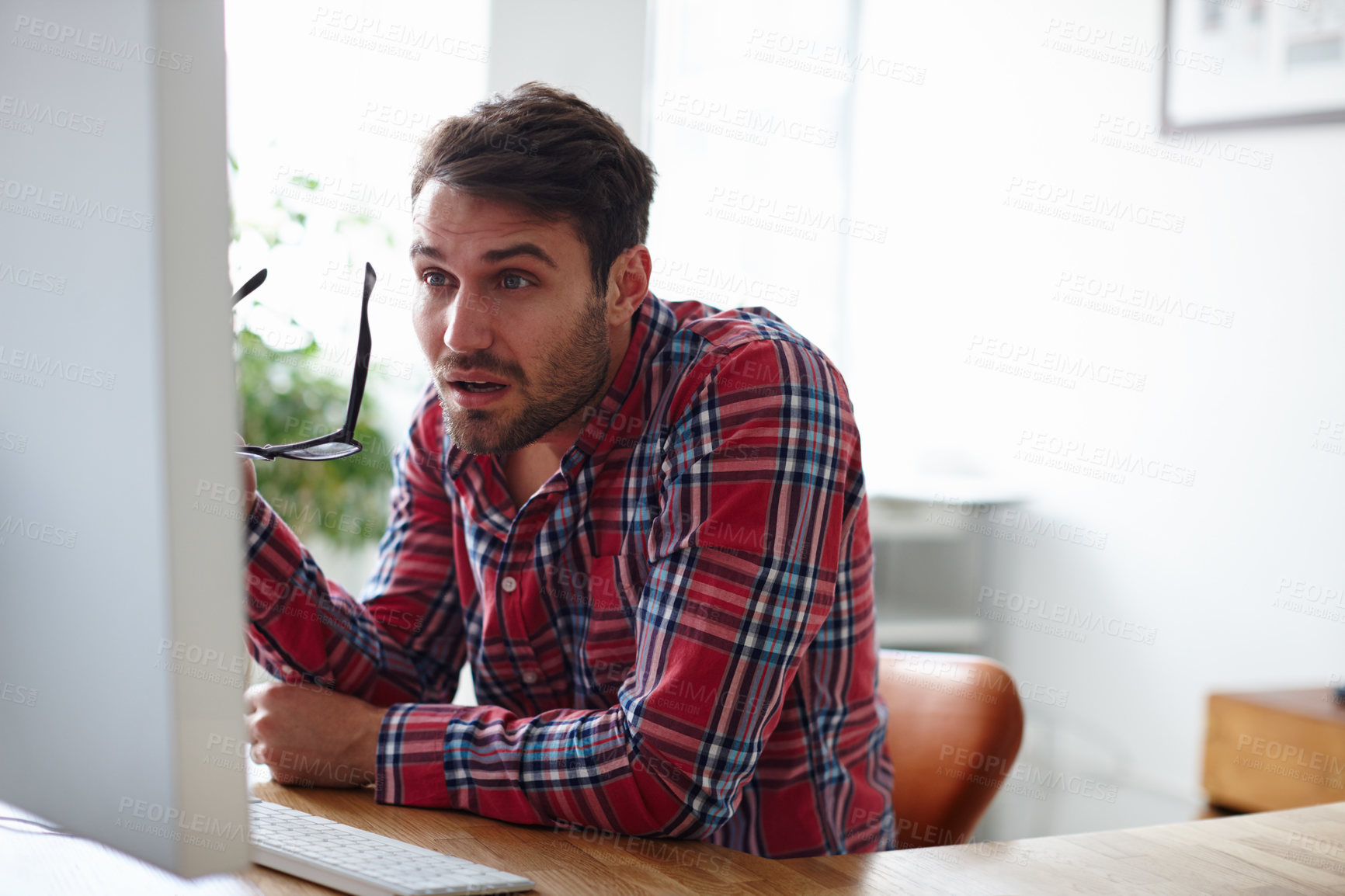 Buy stock photo Shot of a young designer squinting at the screen of his computer