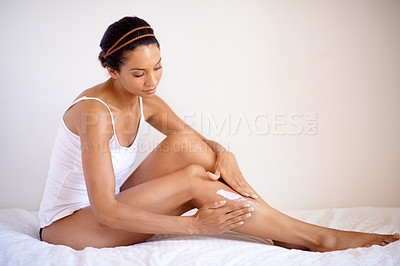 Buy stock photo Black woman, legs and moisturizer creme for skincare, cosmetics or self love and care in relax at home on bed. African American woman applying lotion for healthy, soft or smooth leg skin in bedroom