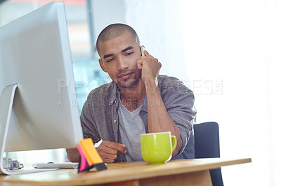 Buy stock photo Shot of a designer talking on a cellphone while working on a computer in an office