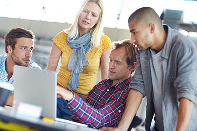 Buy stock photo Shot of a diverse group of designers working on a laptop in an office