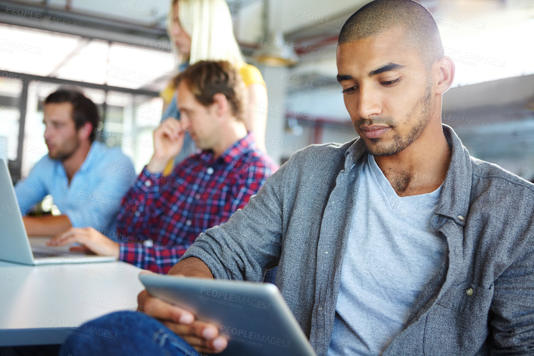 Buy stock photo Shot of a designer using a digital tablet with colleagues in the background