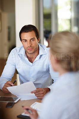 Buy stock photo Shot of a businessman holding a document while sitting in a meeting with colleagues