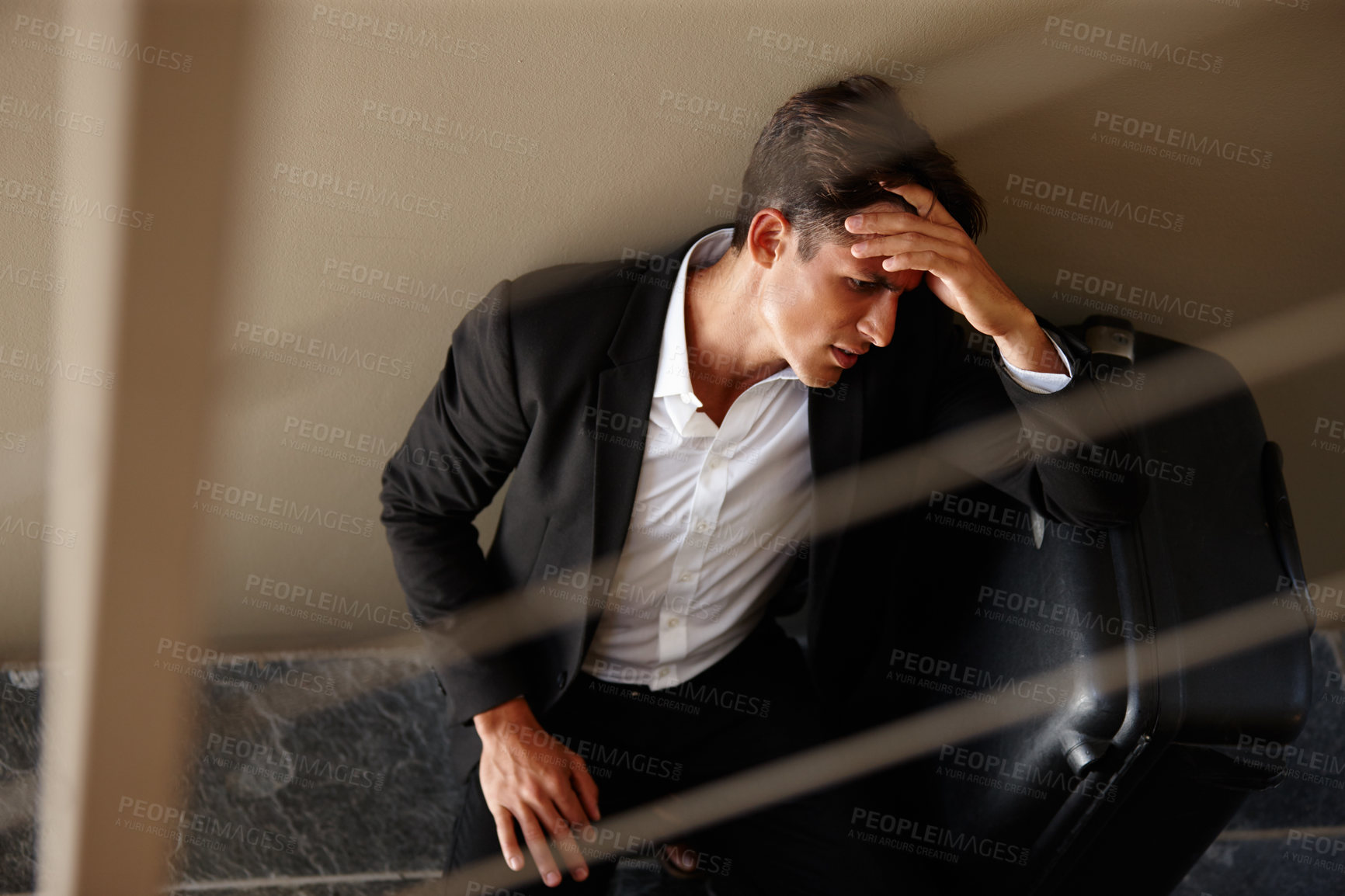 Buy stock photo Shot of an exhausted young businessman sitting on the floor beside his luggage