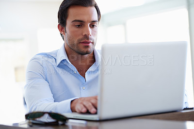 Buy stock photo Shot of a handsome businessman working on his laptop at his desk