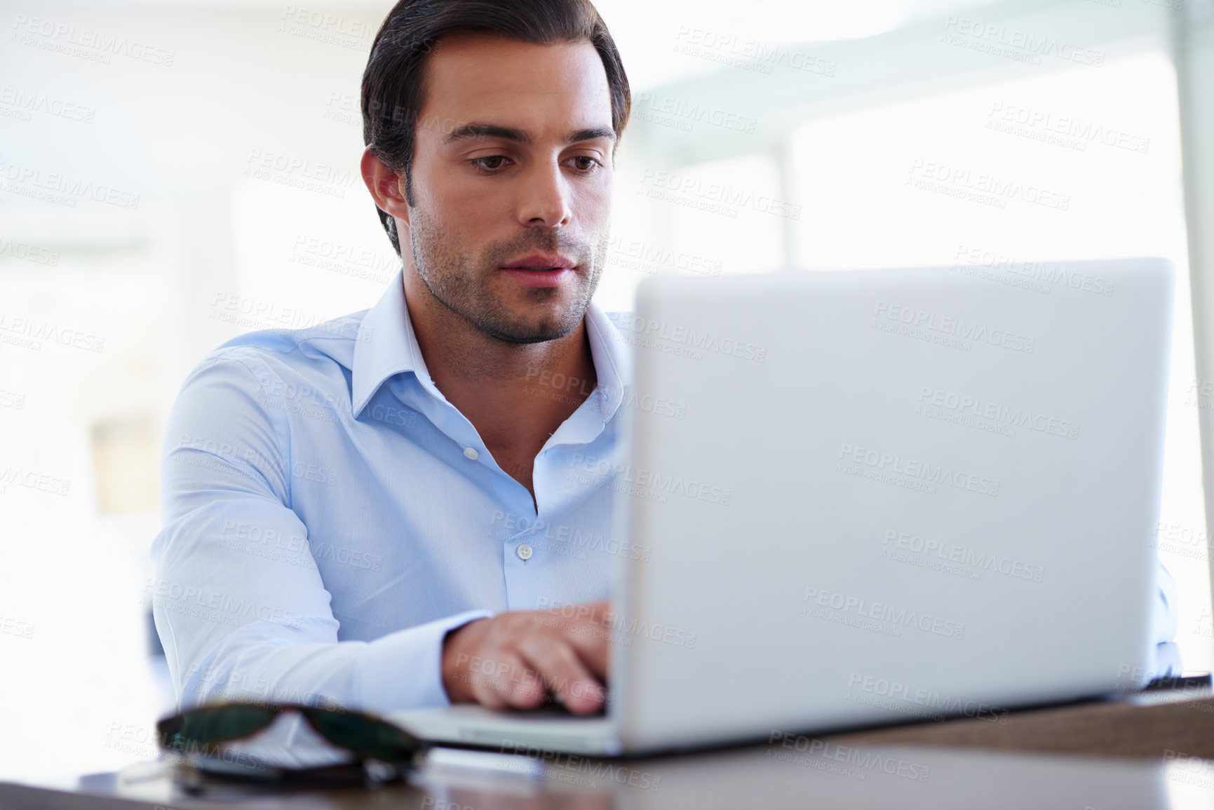 Buy stock photo Shot of a handsome businessman working on his laptop at his desk