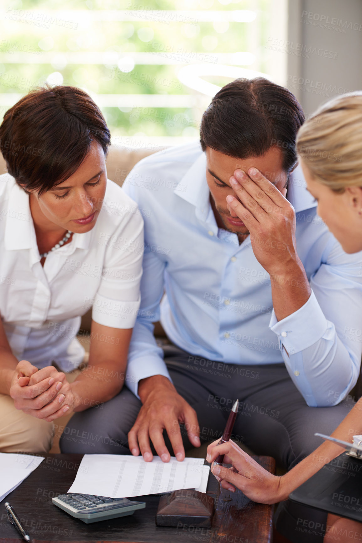 Buy stock photo Shot of a couple looking worried while discussing their finances with a financial advisor